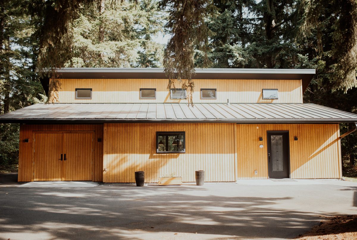 Front elevation of the cedar-clad cabin beneath the surrounding trees