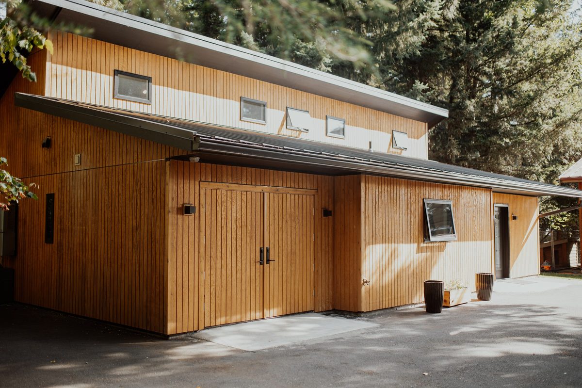 Angled view of the cabin's cedar exterior, custom doors, and raised roofline