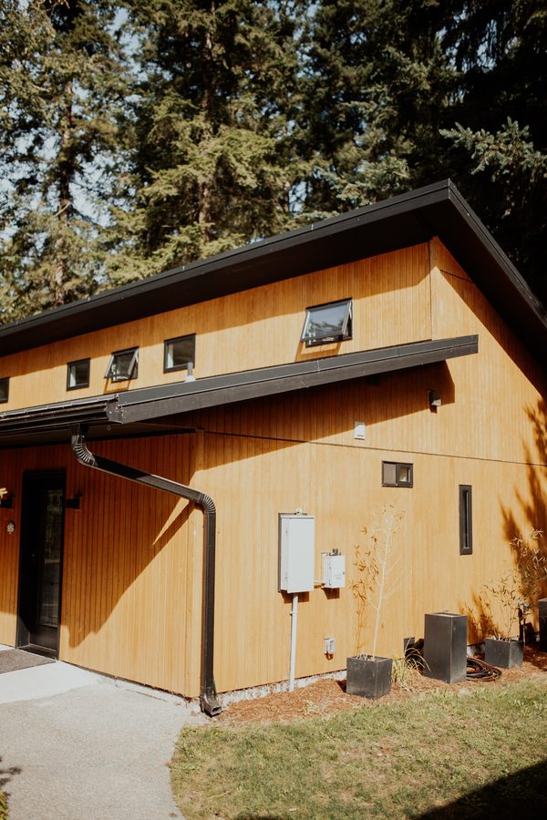 Cabin end elevation showing the roof profile, cedar siding, and side entrance