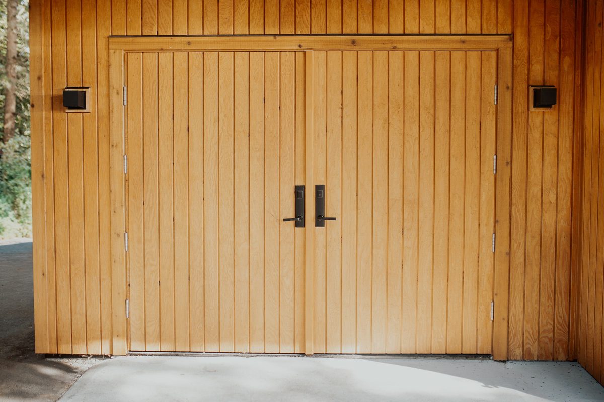 Handmade wide wood doors fitted flush with the cabin's vertical cedar siding