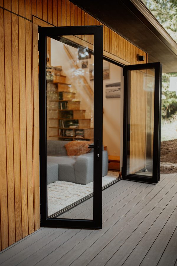 Open folding glass doors along the cedar-clad cabin deck