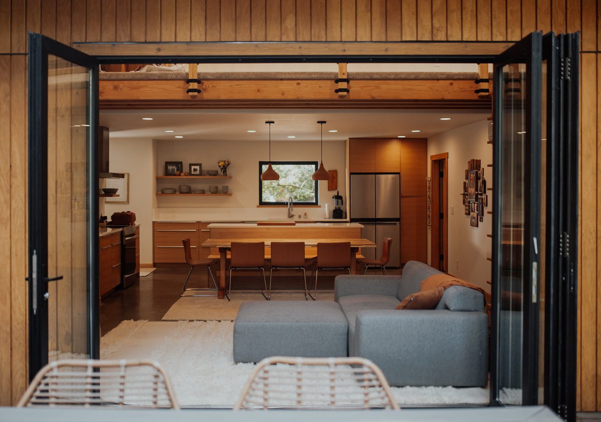 Open glazed doors connect the cabin deck to the living, dining, and kitchen space