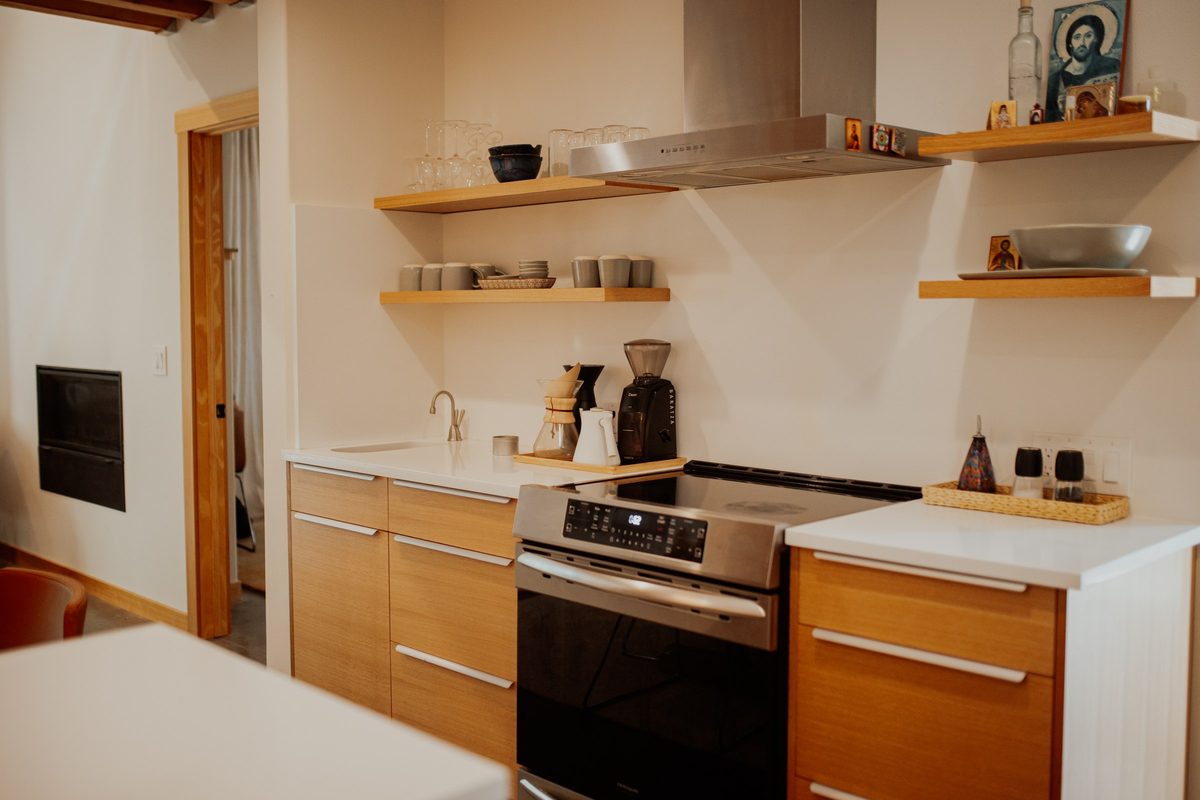 Cabin kitchen range wall with wood cabinetry and floating shelves