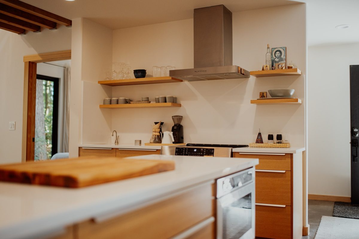 Kitchen island worktop with the range and wood floating shelves beyond