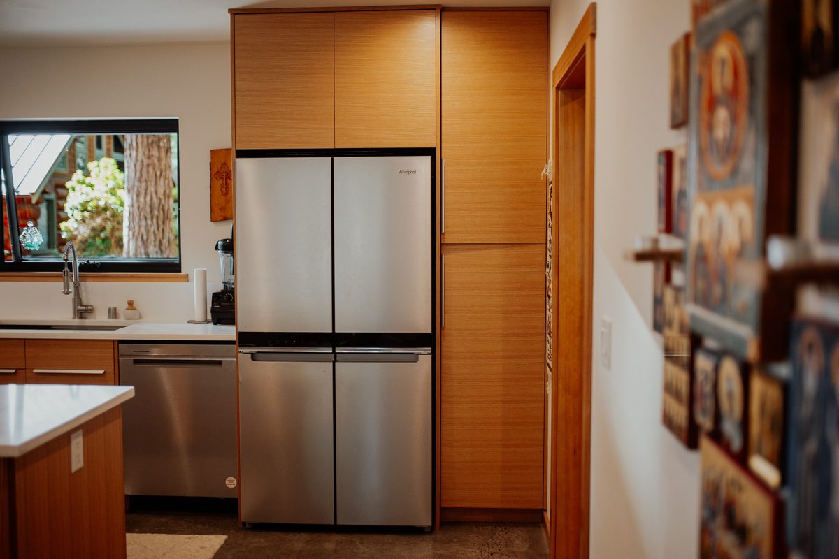 Refrigerator framed by floor-to-ceiling wood cabinetry in the cabin kitchen