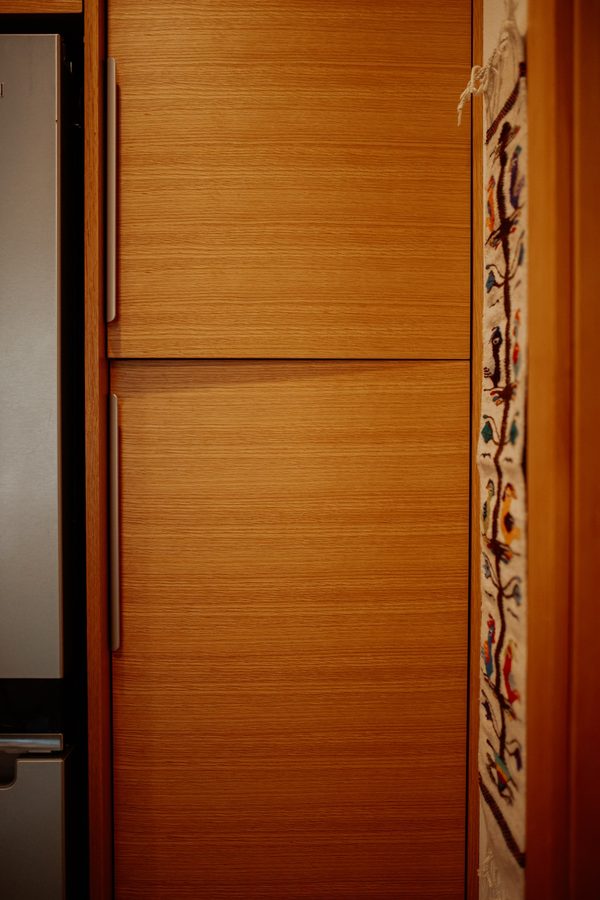 Close view of the wood grain and horizontal reveals on tall kitchen cabinet fronts