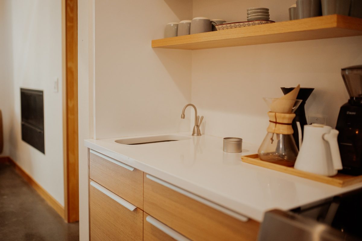 Compact cabin coffee bar with a small sink, wood cabinetry, and floating shelves
