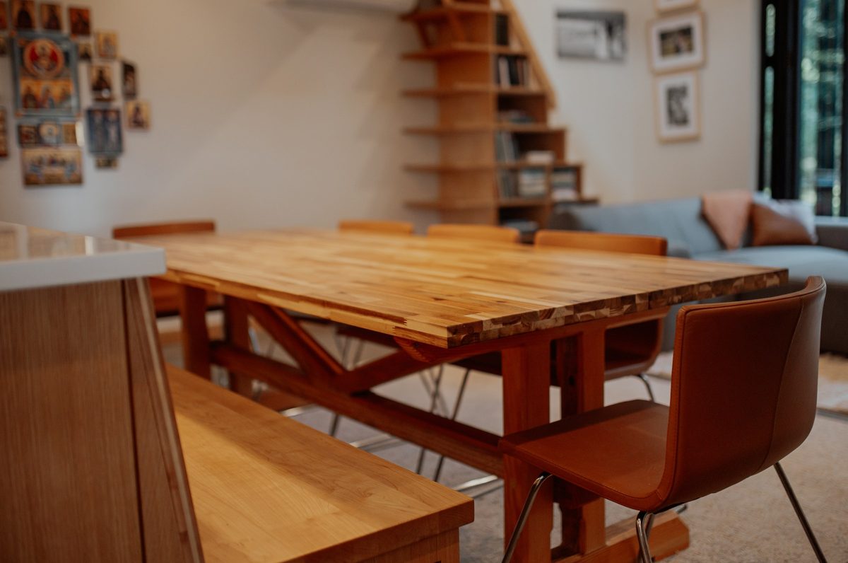Wood dining tabletop with the bookcase staircase in the background