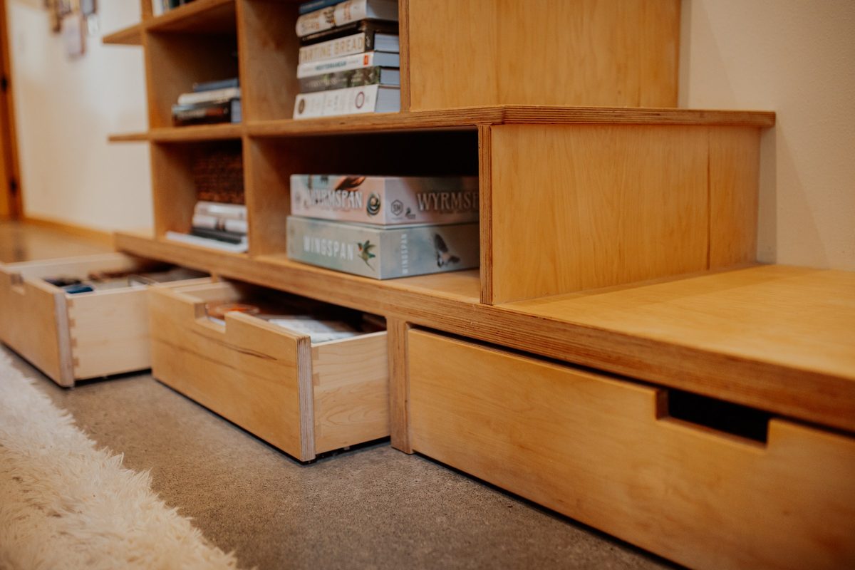 Storage drawers open beneath the custom bookcase staircase