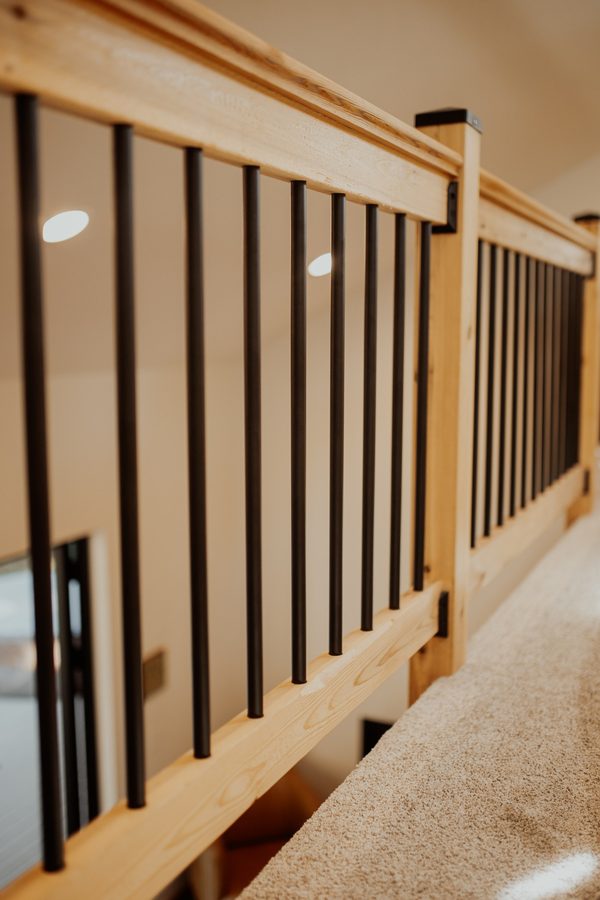 Close view of the loft's wood railing and dark vertical balusters