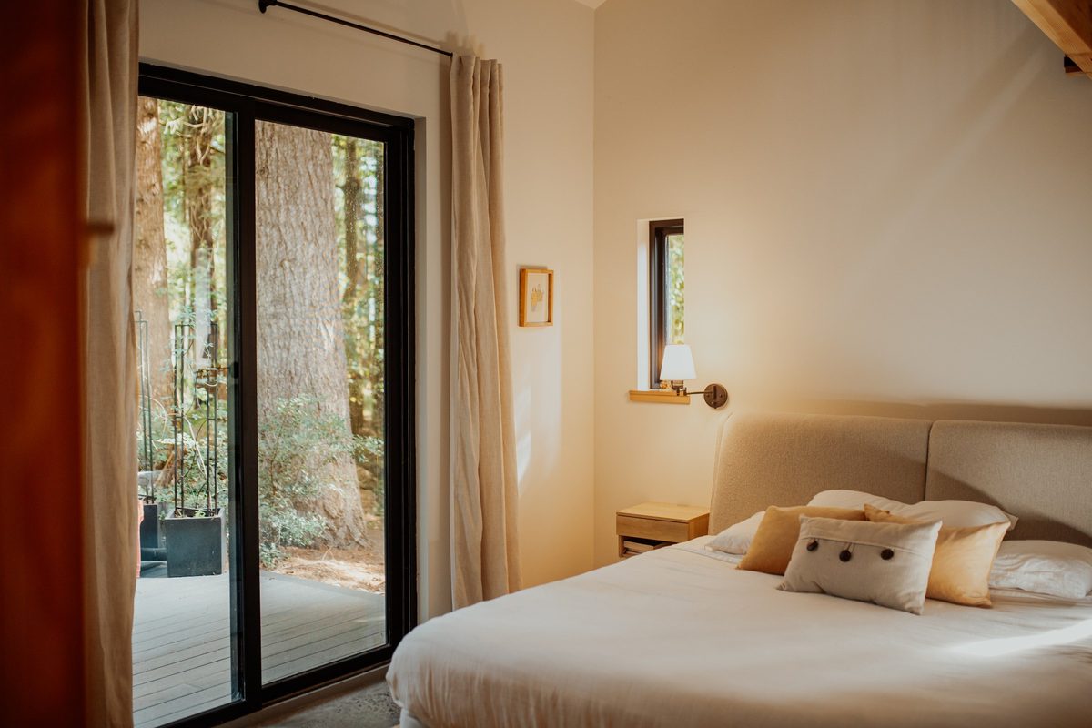 Cabin bedroom with glazed doors opening toward the surrounding trees