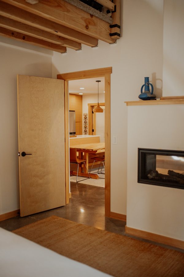 Bedroom looking toward the living area through the wood-trimmed doorway beside the fireplace