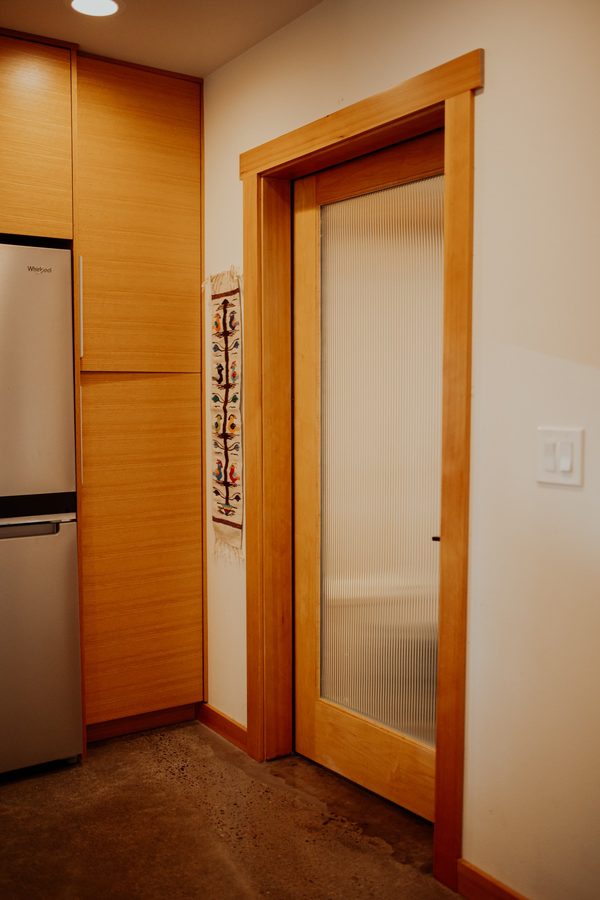 Wood-trimmed interior door beside the tall kitchen cabinetry