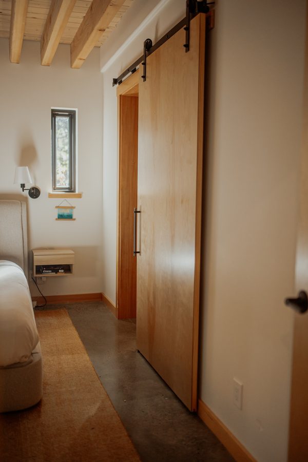 Wood sliding door and track beneath the exposed bedroom ceiling