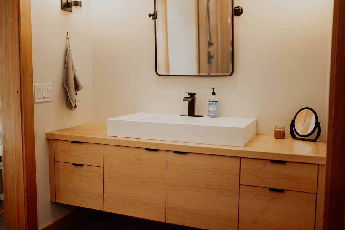 Wood bathroom vanity with a white basin and wall mirror in the Everson cabin