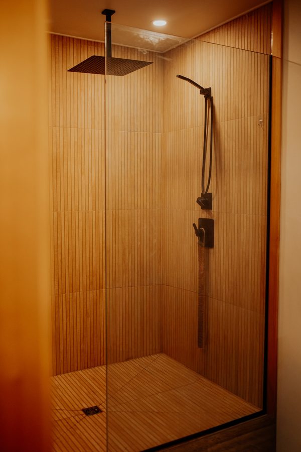 Cabin shower with vertically textured wall tile, a tiled floor, and dark fixtures
