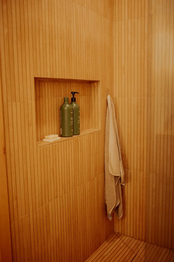 Recessed niche integrated into the shower's vertically textured tile wall